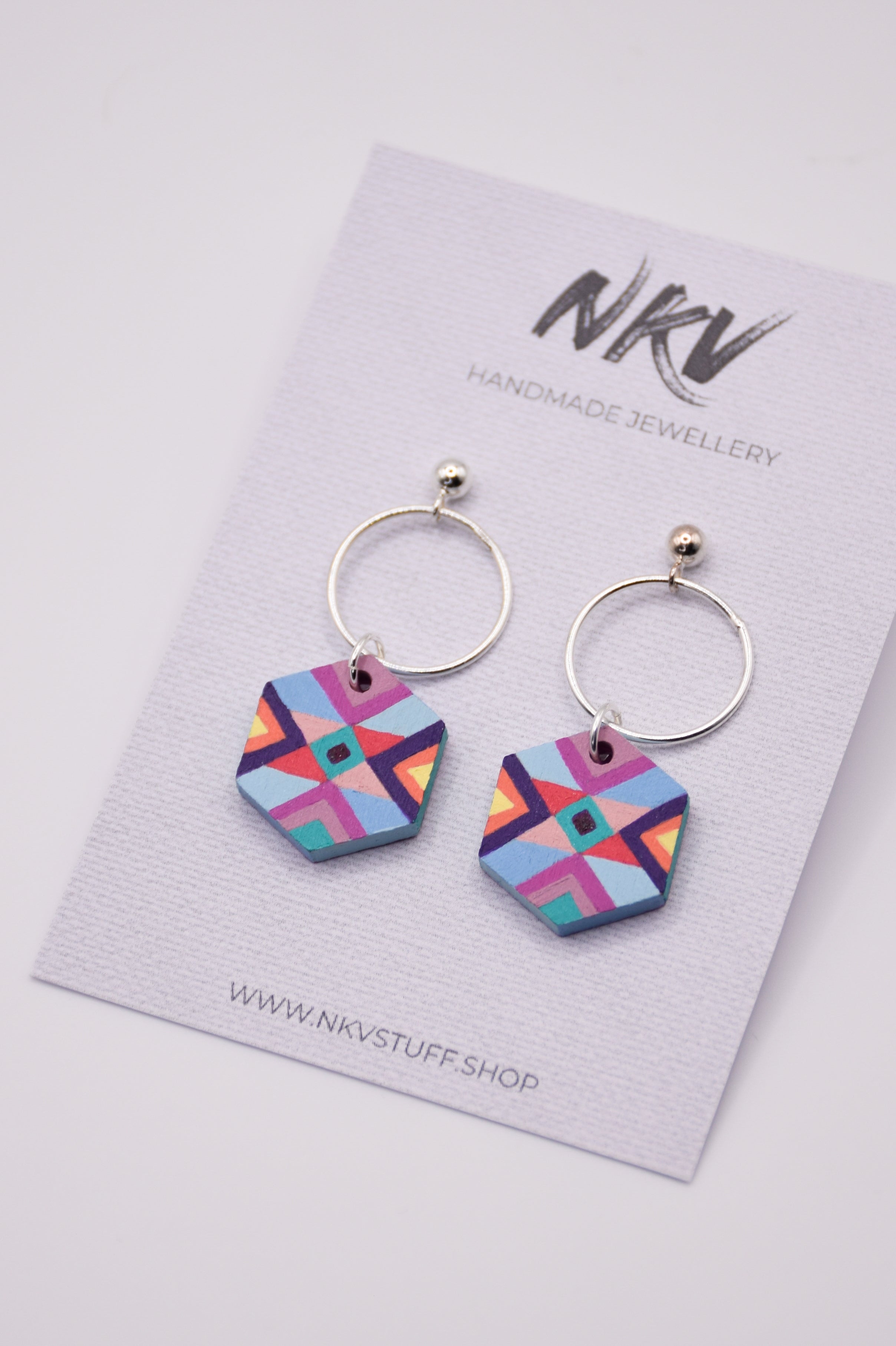 Hexagonal hand-painted wooden earrings in purple and blue colours with silver hoops