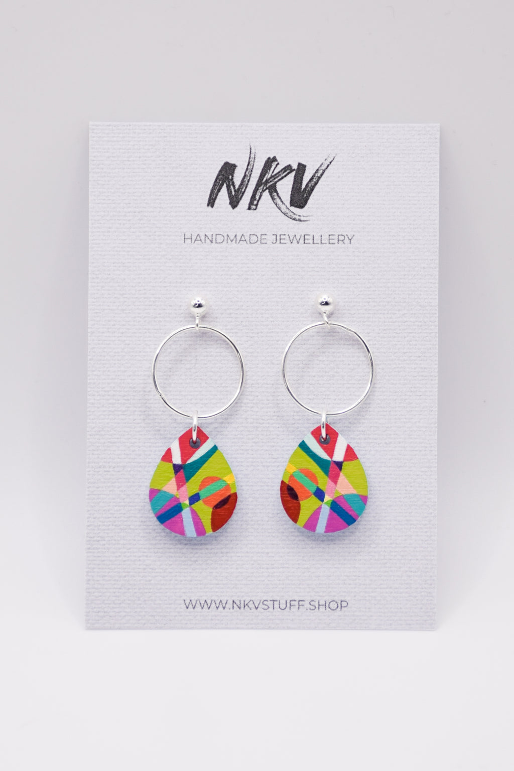 Colorful hand-painted teardrop earrings with silver hoops on a NKV branded card 