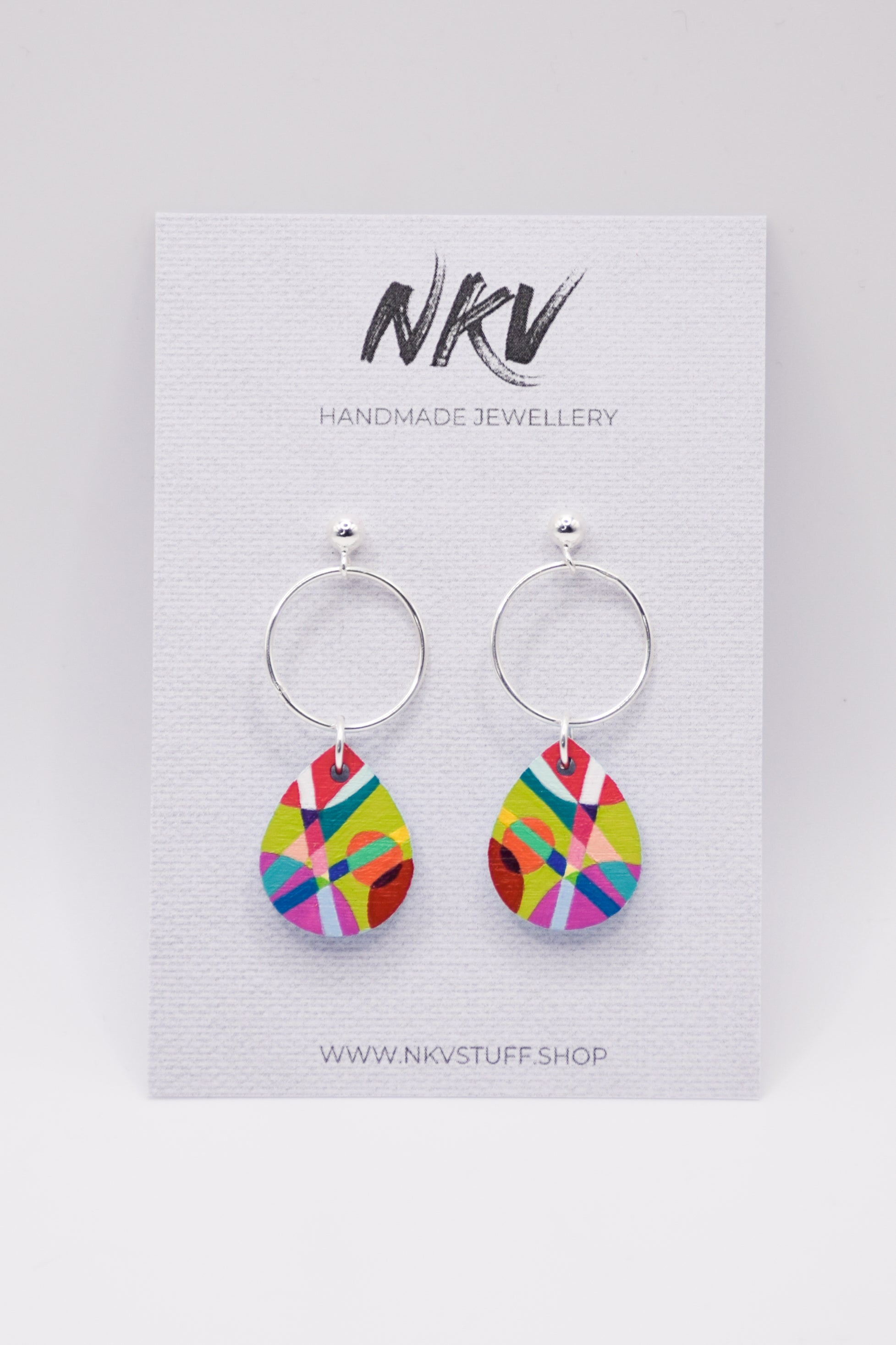 Colorful hand-painted teardrop earrings with silver hoops on a NKV branded card 