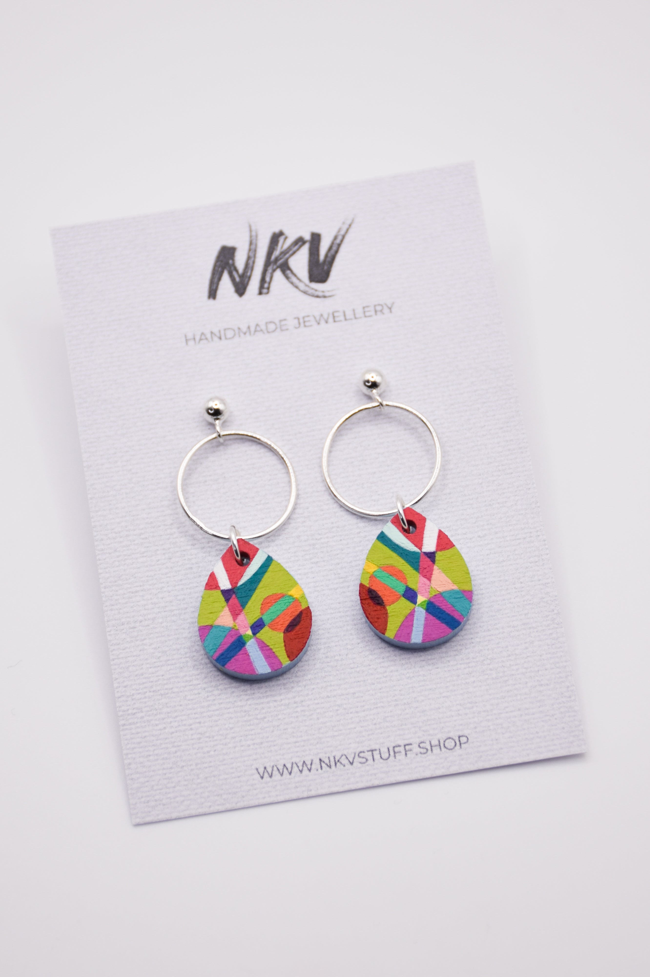 Colorful hand-painted teardrop earrings with silver hoops on a NKV branded card.