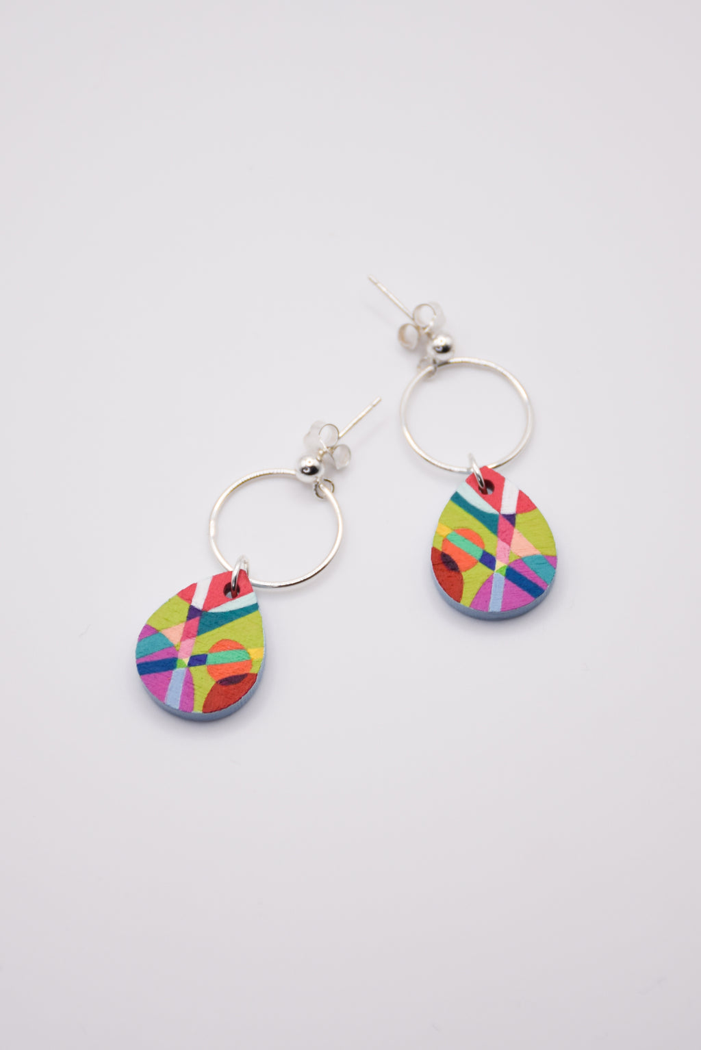Colorful hand-painted teardrop earrings with silver hoops on a light gray background